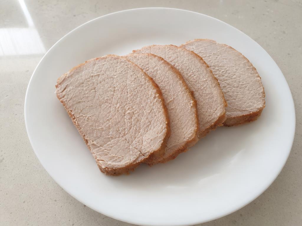 Slices of plain thoroughly cooked unseasoned pork loin on a white ceramic plate