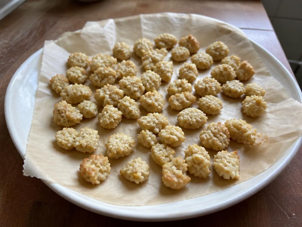 Small pale-golden baked chicken and rice dog treat bites on a parchment-lined plate