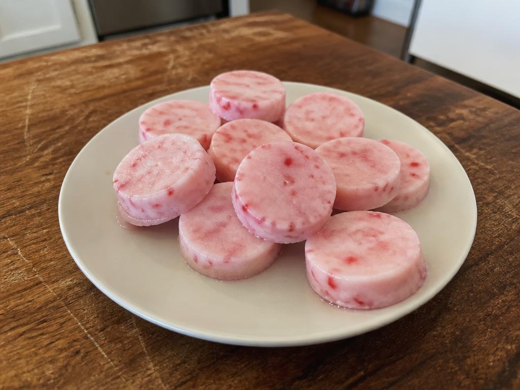 Small pink and cream frozen strawberry yogurt dog treats on a plate