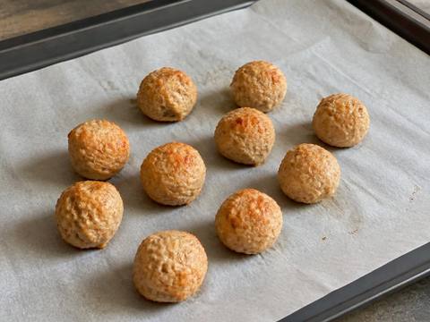 Small plain cooked turkey and pumpkin meatballs on a parchment-lined baking tray, with no sauce or garnish