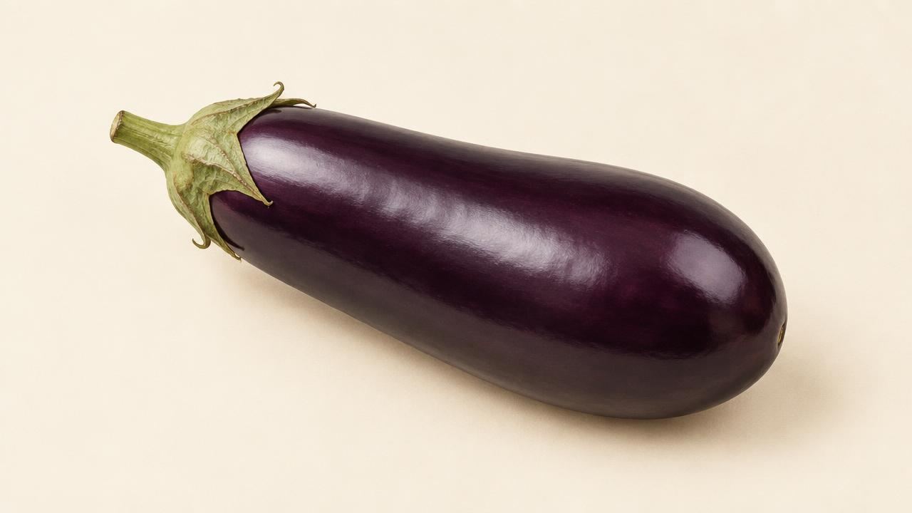 A whole glossy purple eggplant (aubergine) on a cream surface