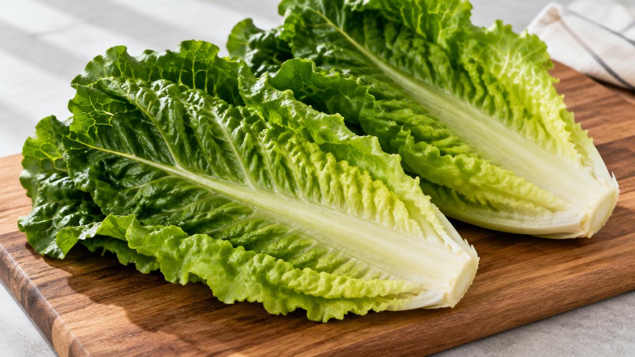 Fresh romaine lettuce leaves on a wooden cutting board.