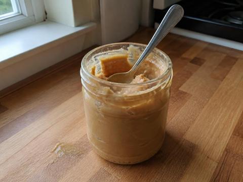 A jar of natural peanut butter with a spoon