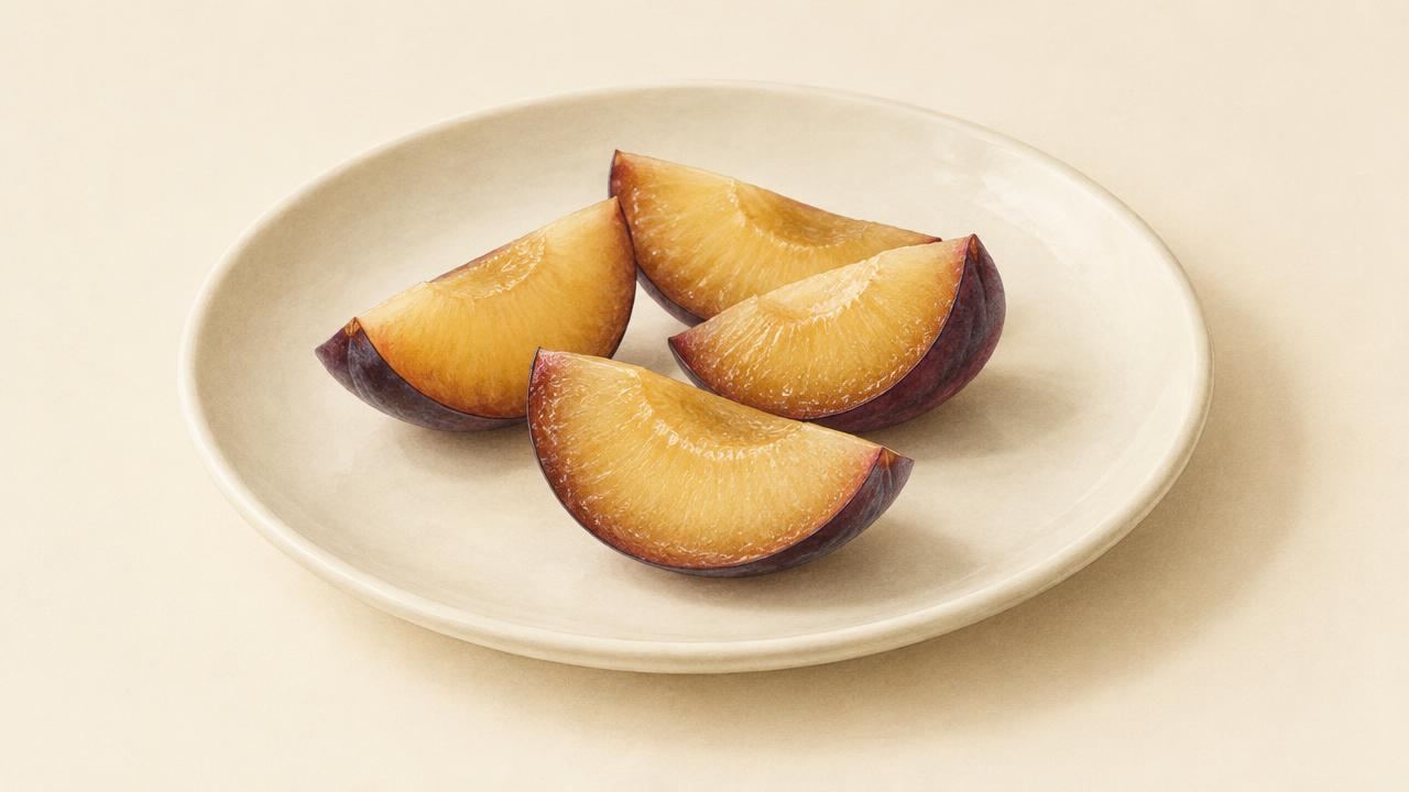 A few slices of ripe plum flesh, with no pits, on a cream plate